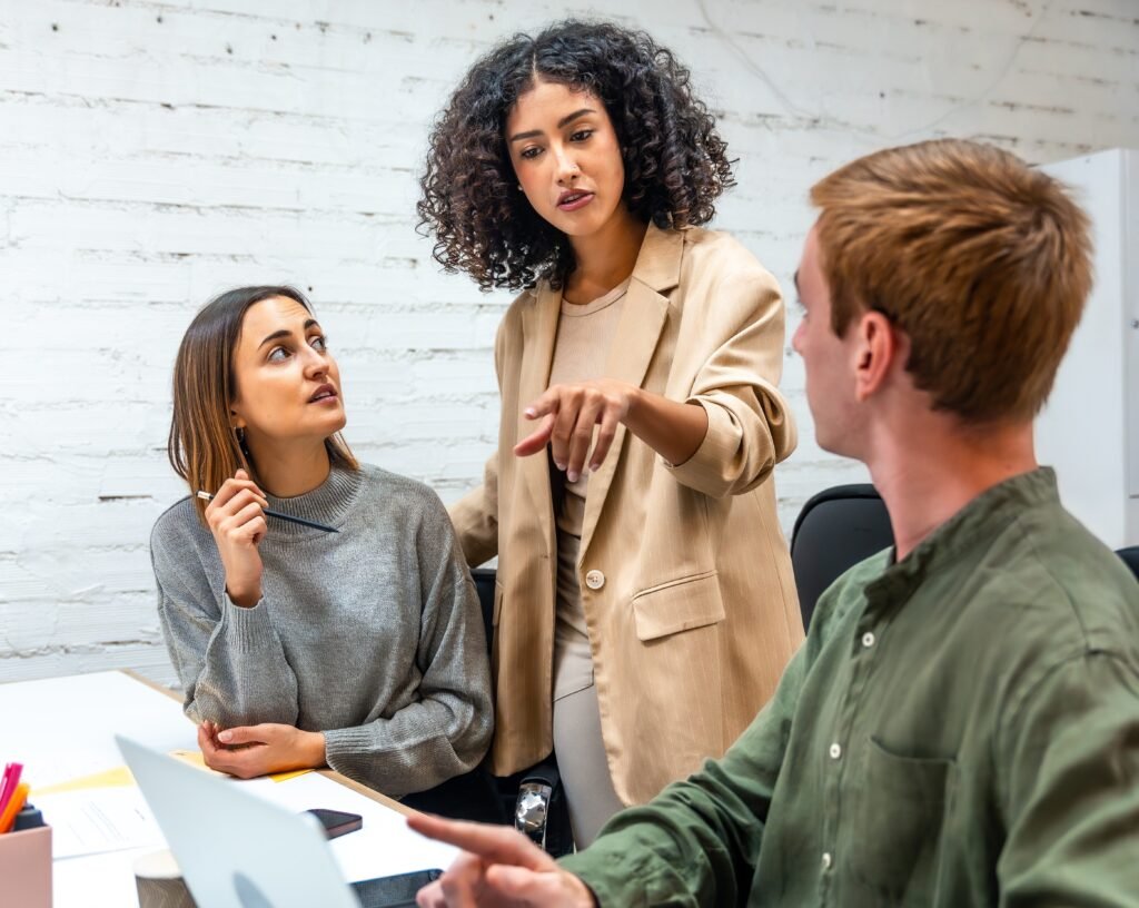 Vertical photo of an hispanic female boss scolding two employees in a coworking space